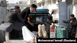 Men carry an injured person to the hospital after attacks in Kabul on March 7.