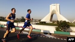 Runners in Iran's first international marathon pass Azadi Square in Tehran.