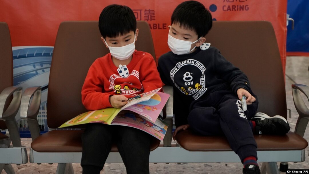 Copii purtând mască pentru a se păzi de coronavirus, într-o gară din Hong Kong