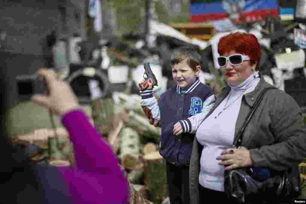 A boy with toy gun poses for picture in front of barricades at the police headquarters in the eastern town of Slovyansk, Ukraine, on April 17. (Reuters/Gleb Garanich)