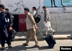 Afghan passengers walk toward the airport in Kabul on August 15.