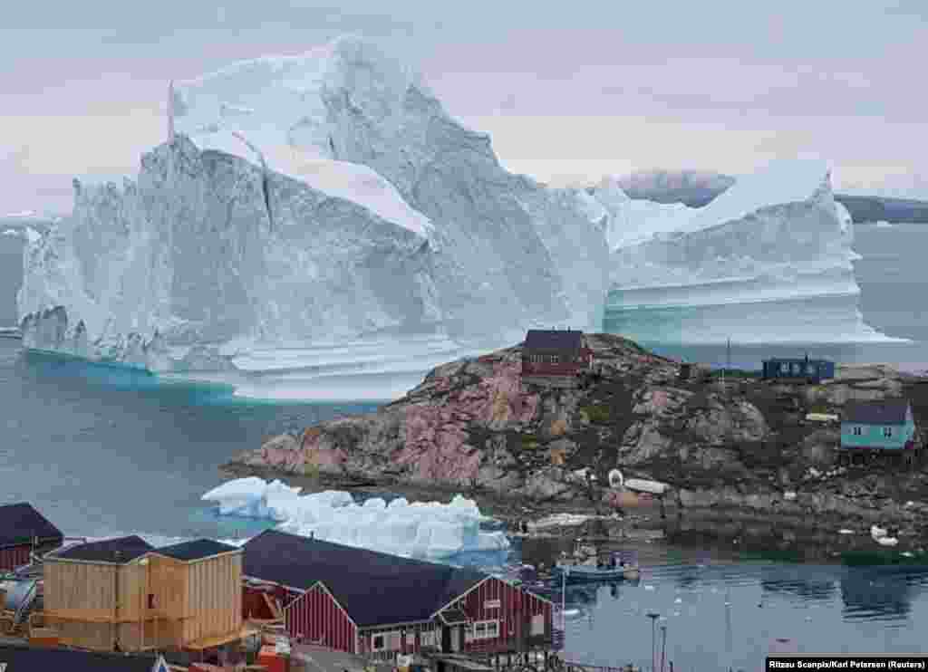 A giant iceberg is seen behind an Innaarsuit settlement in Greenland. (Reuters/Ritzau Scanpix/Karl Petersen)