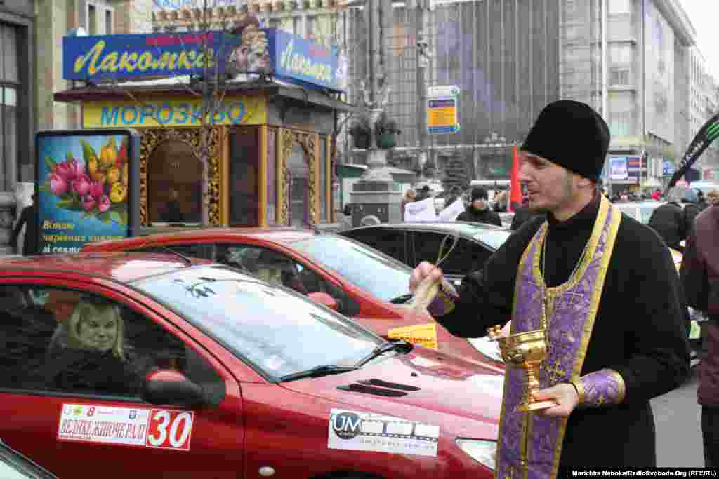 Священик освячує автівки перед стартом