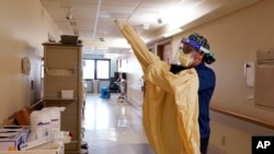 Медсестра надевает защитный костюм перед тем, как войти в палату. Иллюстративное фото.