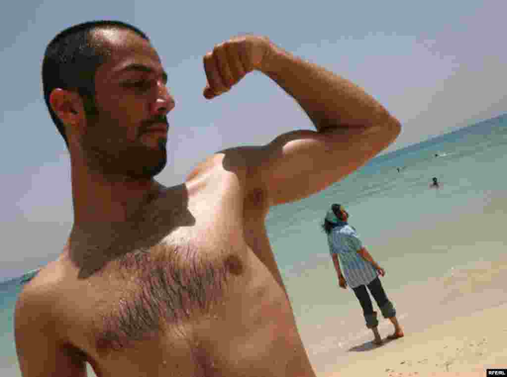 Iran, A guy showing off his mussel to the camera on the beach of Caspian sea, undated