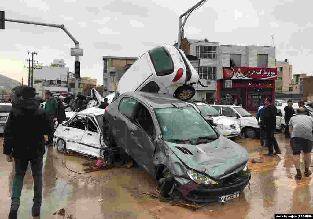 People stand near destroyed cars after a flash flood hit the Iranian city of Shiraz on March 25. (epa-EFE/Amin Berenjkar)