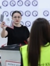 Një zyrtare e Komisionit Qendror të Zgjedhjeve vëzhgon teksa një qytetare e hedh votën e saj në kutinë e votimit në zgjedhjet e parakohshme parlamentare të 7 qershorit, në një qendër votimi në Prishtinë, 7 qershor 2026.