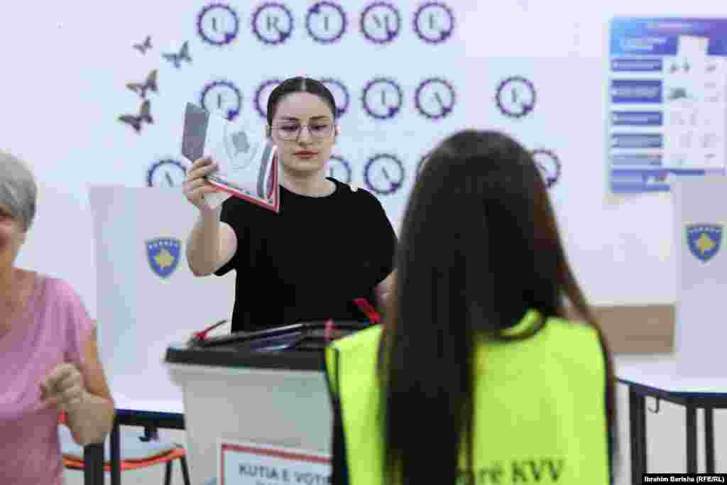 Službenica Centralne izborne komisije posmatra dok građanka ubacuje glasački listić u glasačku kutiju na prijevremenim parlamentarnim izborima 7. juna, na biračkom mjestu u Prištini, 7. juna 2026.