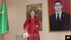 A woman casts her ballot at a polling station in Ashgabat on March 26 featuring a portrait of President Serdar Berdymukhammedov.