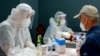 Medical workers in protective suits admit patients at a new day hospital Bishkek in July.