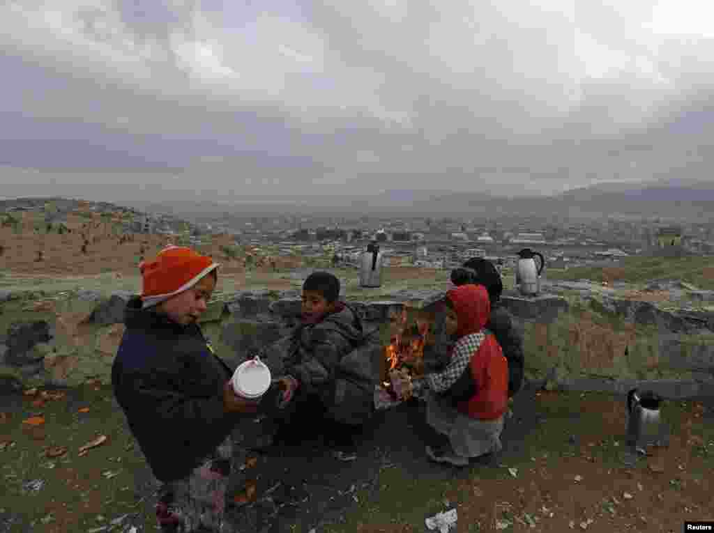 Afghan children who are selling tea warm themselves by a fire on a cold day in Kabul. A tea vendor earns $1 a day on average. (Reuters/Mohammad Ismail)