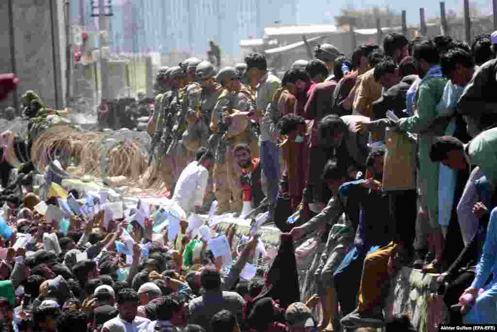 Afghans struggle to reach foreign forces to show their credentials to flee the country outside the Kabul airport, shortly before a suicide bomber killed at least 60 Afghans at the airport on August 26.