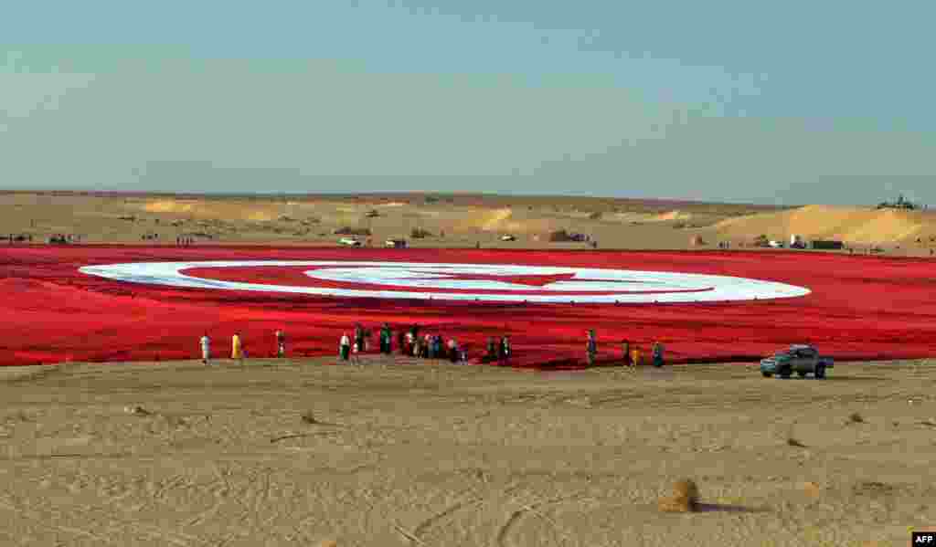 A giant Tunisian national flag is unfurled at Ong Jmel in the southern desert. The flag is the size of 19 football pitches and is a bid to set a Guinness world record and promote patriotism in the face of Islamist extremism. (AFP/Saif Trabelsi)