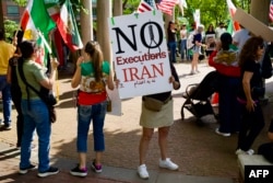 Demonstrators hold signs as they gather during a rally in Washington, DC on May 16 to condemn the execution of political prisoners in Iran.