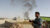 An Afghan policeman stands guard as smoke rises from the site of a bomb attack last month in Ghazni Province. (file photo)