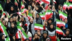 Women wave Iranian national flags as they attend President Hassan Rouhani's public speech in Bandar Kangan, Iran March 17, 2019