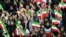 Women wave Iranian national flags as they attend President Hassan Rouhani's public speech in Bandar Kangan, Iran March 17, 2019