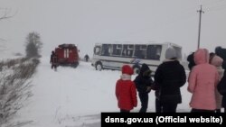 Діти дивляться, як рятувальники витягують із замету шкільний автобус на Волині, 26 січня 2021 року