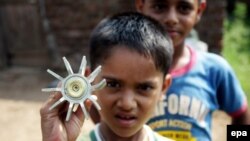 An young Indian holds the tail of a mortar shell allegedly fired from the Pakistani side of the Kashmir border into the Indian administered Kashmir.