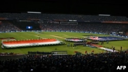 د هند او نیو زیلینډ د کرکټ لوبغاړي د ۲۰ اووره نړیوال جام تر پایلوبې مخکې له بیرغونو سره د ملي سرود لپاره ولاړ دي - د مارچ اتمې انځور. 