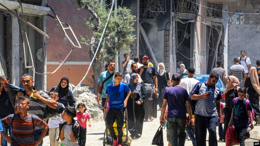 În imagine, oameni care pleacă dintr-o tabără de refugiați din centrul Fâșiei Gaza, marți 23 iulie, în urma bombardamentelor armatei israeliene.