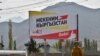 A woman walks in front of a campaign billboard for Mekenim Kyrgyzstan in the village of Koi-Tash, outside Bishkek.