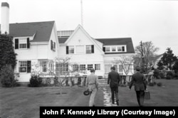 Military aide General Chester Clifton (right) carries the first iteration of the football alongside U.S. President John F. Kennedy (center) in Hyannis Port, Massachusetts, in May 1963.