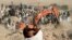 An excavator removes mud from a collapsed house amid the search for victims after an earthquake in the Zindah Jan district of Herat Province in western Afghanistan. 