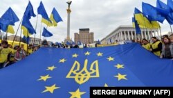 Молодь тримає прапор ЄС з гербом України посередині на майдані Незалежності в Києві, фото архівне