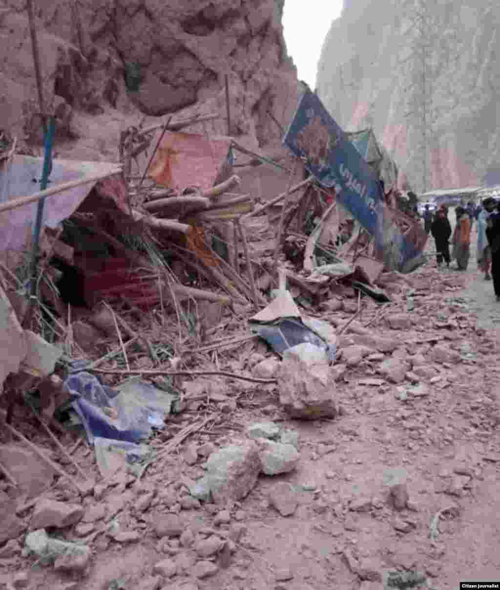 بازارچه‌ای که در امتداد جادۀ تنگی تاشقرغان در شمال افغانستان در نتیجۀ زلزله و رانش سنگ‌ها از کوه تخریب شده است.