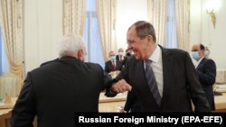 Russian Foreign Minister Sergei Lavrov (R) and Iranian Foreign Minister Mohammad Javad Zarif greet each other "corona style" during a meeting in Moscow, July 21, 2020