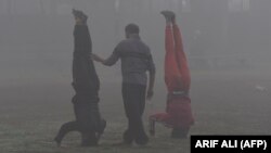 Poluare în Lahore, Pakistan, și lumea cu capul în jos: exerciții de gimnastică în parc, pe fundal de smog industrial. Duminică se deschide în Glasgow, Scoția, conferința COP26 a "ultimei șanse" pentru salvarea planetei.