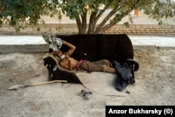 Egy férfi egy fa árnyékában keres menedéket a perzselő nap elől Khivában