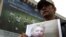 An opposition supporter holds a photo of former Prime Minister Yulia Tymoshenko in front of a billboard for Euro 2012 in Kyiv.