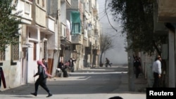 People run for cover from smoke after a shelling in the Karm al-Zeitoun area in Homs, Syria.