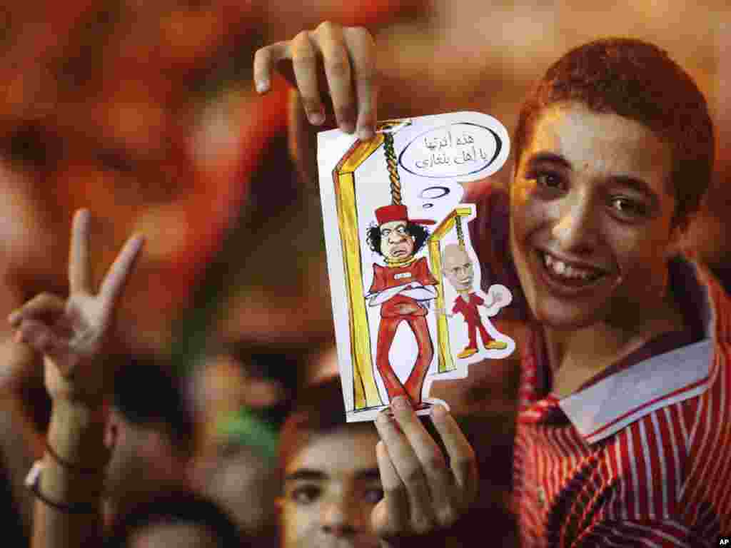 A boy in Benghazi holds a drawing depicting Qaddafi and his son Saif al-Islam being hanged.