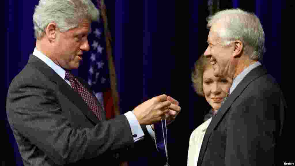 Bill Clinton elnök az Elnöki Szabadság Érdemérmmel tünteti ki Jimmy Cartert az atlantai Carter Központban 1999. augusztus 9-én. Carter az&nbsp;elnöki hivatal elhagyása után létrehozta a Carter Center nevű szervezetet, amely a békefolyamatok előmozdításán és az emberi jogok védelmén dolgozik világszerte