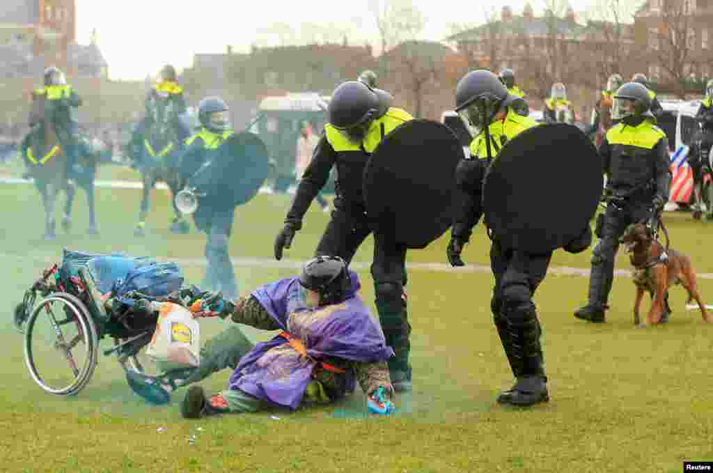 Një grua është rrëzuar në tokë derisa policia intervenoi për të shpërndarë protestuesit në Amsterdam të Holandës, më 24 janar 2021.&nbsp;