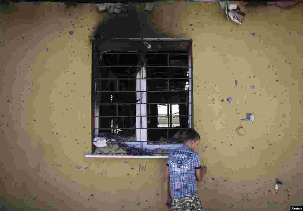 A boy collects bullets and empty cartridges next to abandoned buildings of the Ukrainian border-guard regional headquarters damaged in a recent fight with pro-Russian separatists, on the outskirts of Luhansk, on June 8. (Reuters/Shamil Zhumatov)