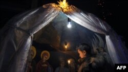 A boy holds a candle during an Orthodox service in a church in Bishkek, Kyrgyzstan, on Christmas eve.