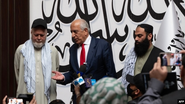 دنیس کویل، شهروند امریکایی (چپ)، پس از آزادی از سوی طالبان در یک نشست خبری با رسانه‌ها صحبت می‌کند. در کنار او زلمی خلیلزاد، نماینده پیشین ویژه ایالات متحده در امور افغانستان (وسط)، و ابراهیم رحیم (راست)، پسر محمد رحیم آخرین افغان بازداشت‌شده در زندان گوانتانامو،