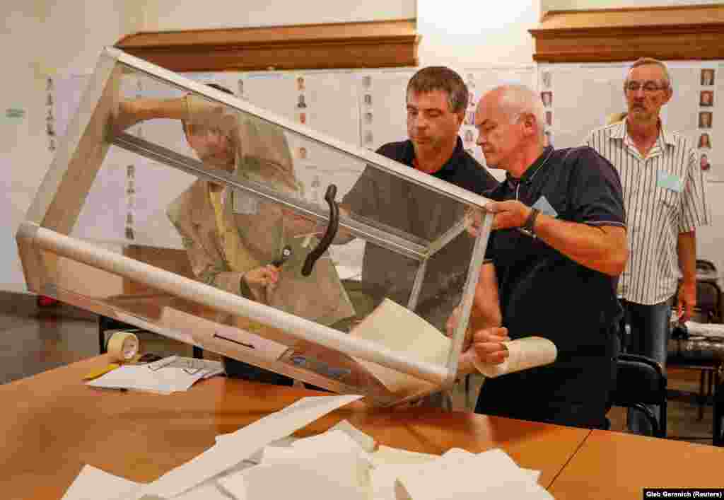 Members of a local electoral commission empty a ballot box at a polling station after a parliamentary election in Kyiv, late on July 21. Preliminary official results are expected by early July 22. (Reuters/Gleb Garanich)