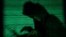 A hooded man holds a laptop computer as cyber code is projected - generic