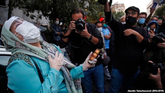 IRAN -- A fan of Iranian legendary singer, instrumentalist, and composer Mohammad-Reza Shajarian holds a picture of him as she mourns in front of the Jam hospital, where Shajarian reportedly passed away, in Tehran, October 8, 2020