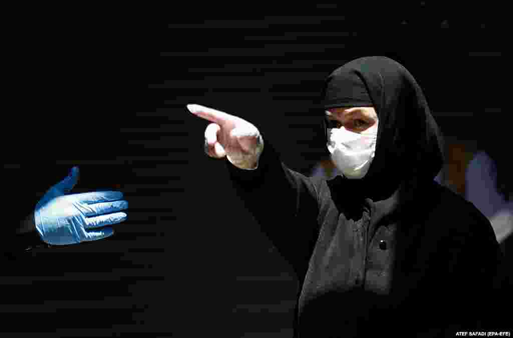 A Greek Orthodox nun, wearing a protective face mask and gloves, gestures while on her way to the Holy Fire ceremony in the church of the Holy Sepulchre, in Jerusalem&#39;s old city on April 18. Eastern Orthodox Christians believe that the Holy Fire emanates from within the Tomb of Christ. Measures were taken by the Israeli government to limit the number of services.