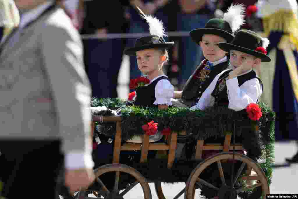 Fëmijë të hipur në një karrocë gjatë paradës së kostumeve tradicionale gjatë aktiviteteve të festivalit Oktoberfest.