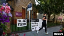 Një person duke vrapuar pranë një qendre votimi në Londër, Britani, 4 korrik 2024.