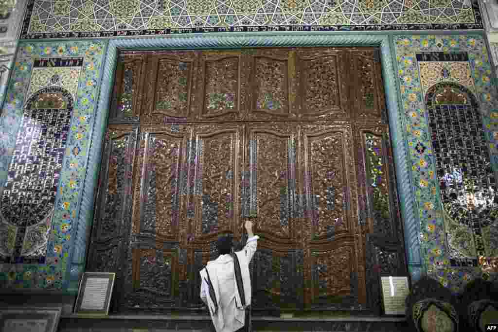 Iranian Jew Eshagh Akhamzadeh locks the door housing the Torah scroll after placing it in inside a cupboard during morning prayers at the Yussef Abad Synagogue.