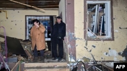 A man and woman stand outside their partially destroyed house after a drone strike on Kharkiv on the evening of May2-3.