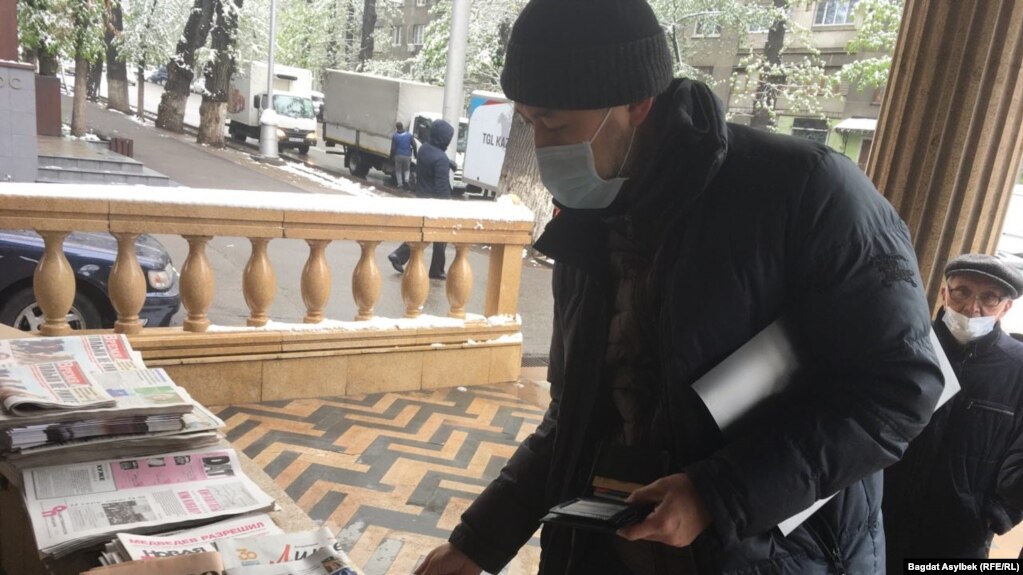 Активист Альнур Ильяшев покупает газету, которую отдаст сотрудникам службы пробации. Алматы, 22 апреля 2021 года
